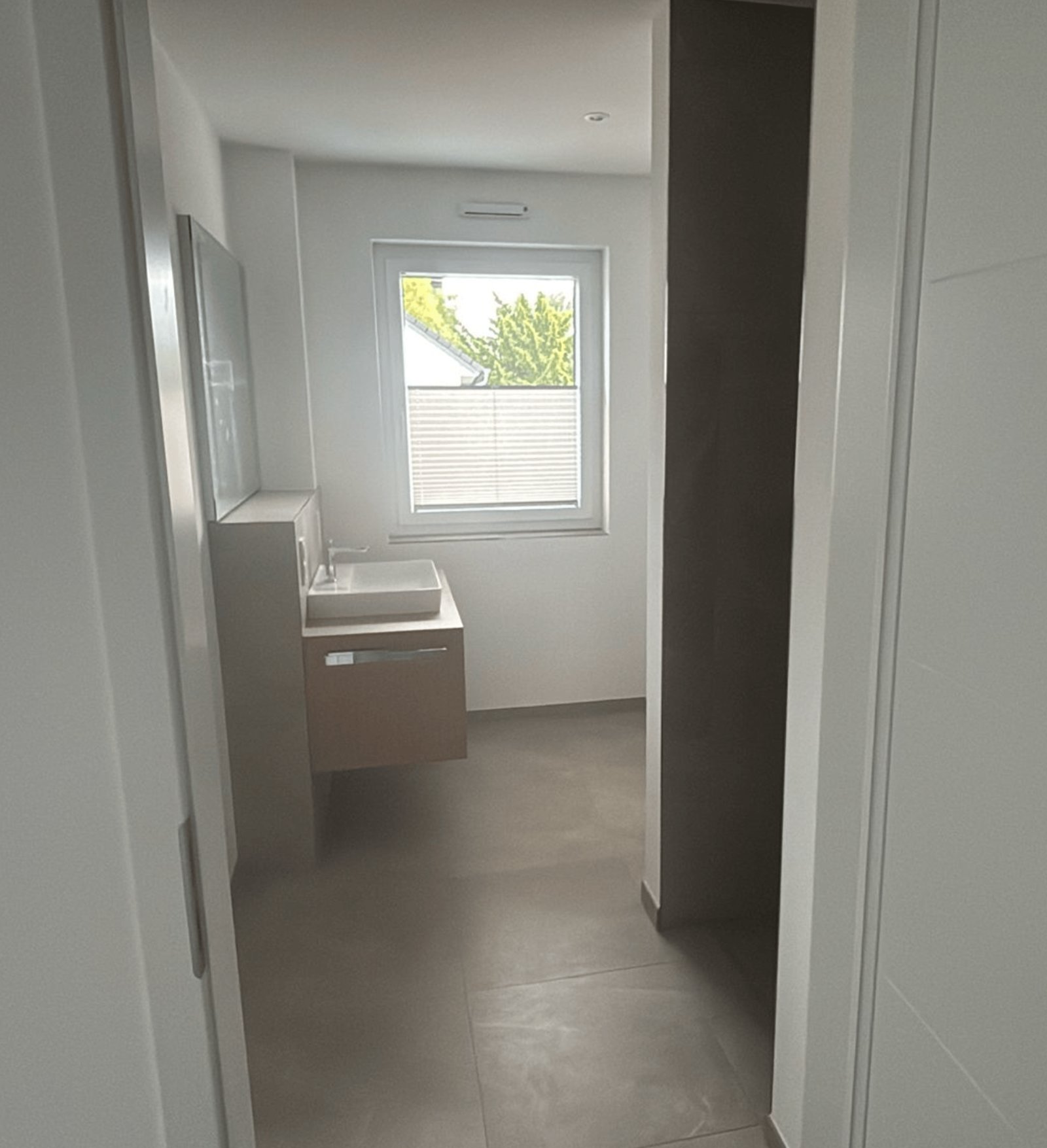 Modernes Badezimmer mit Waschbeckenunterschrank, rechteckigem Waschbecken und Spiegel.