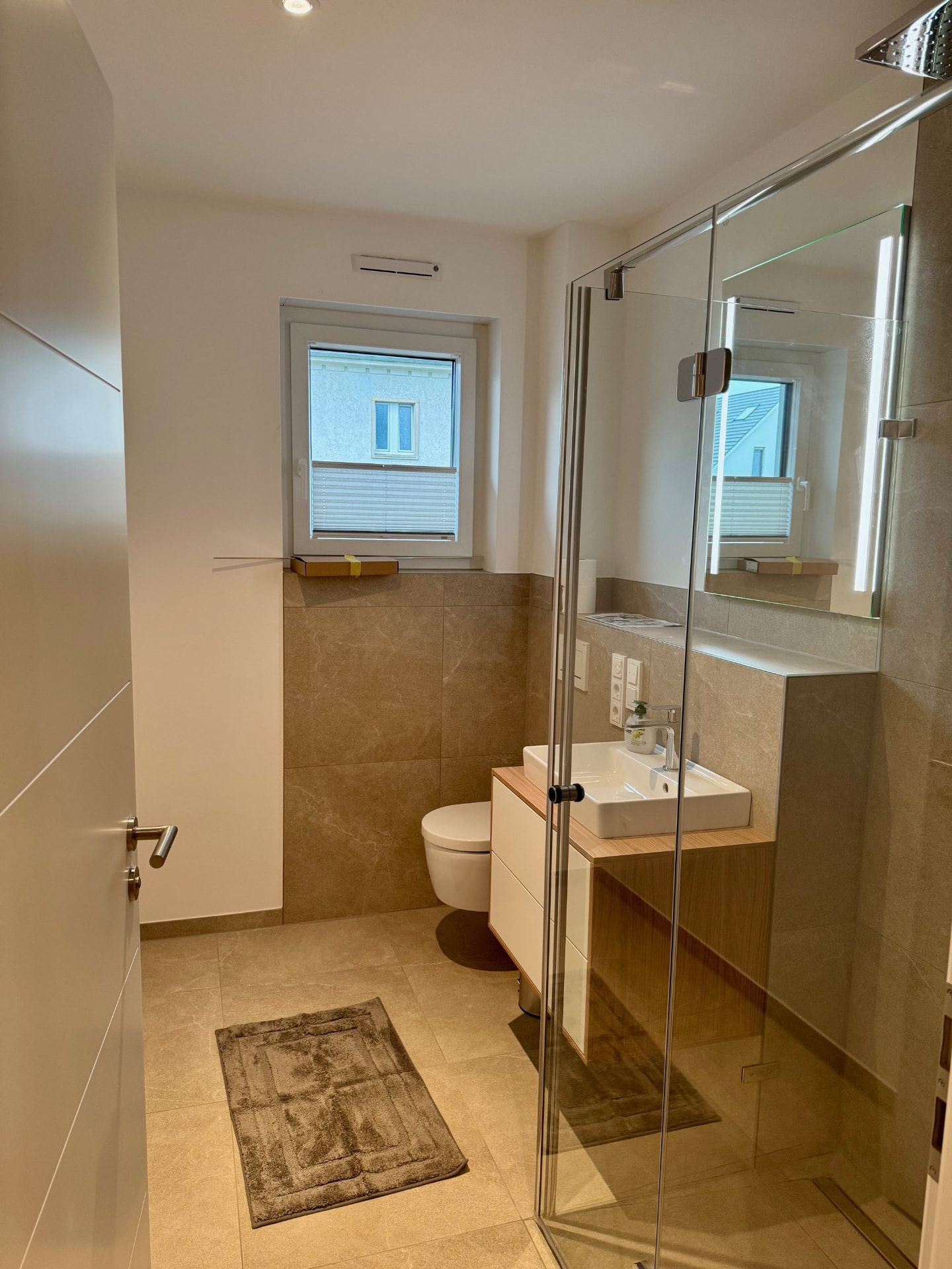 Gäste-Bad mit begehbarer Glasdusche, Wand-WC und Waschtisch auf Eichenplatte.