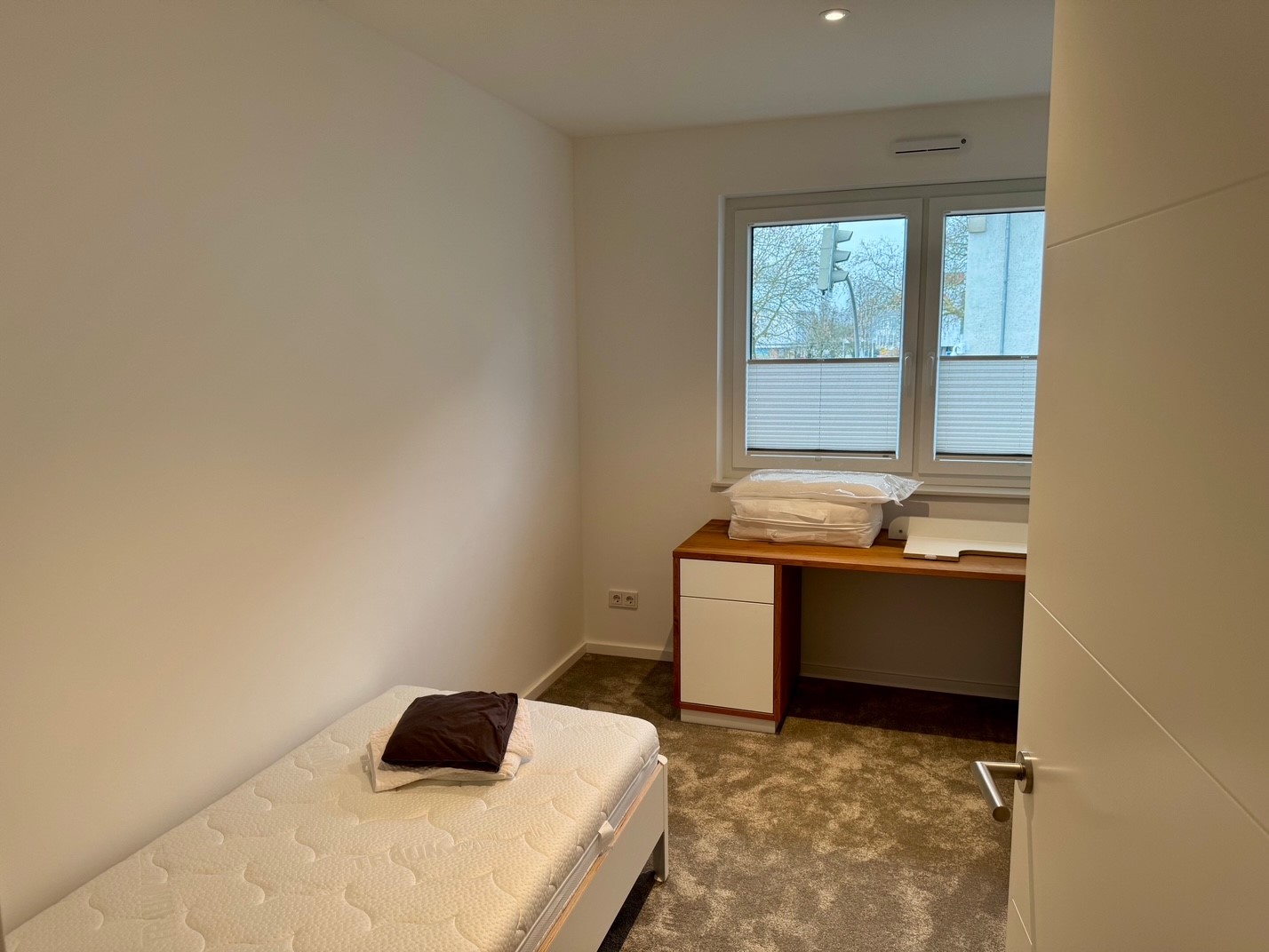 Arbeitsplatz mit Schreibtisch am Fenster und Einzelbett im Gästezimmer.