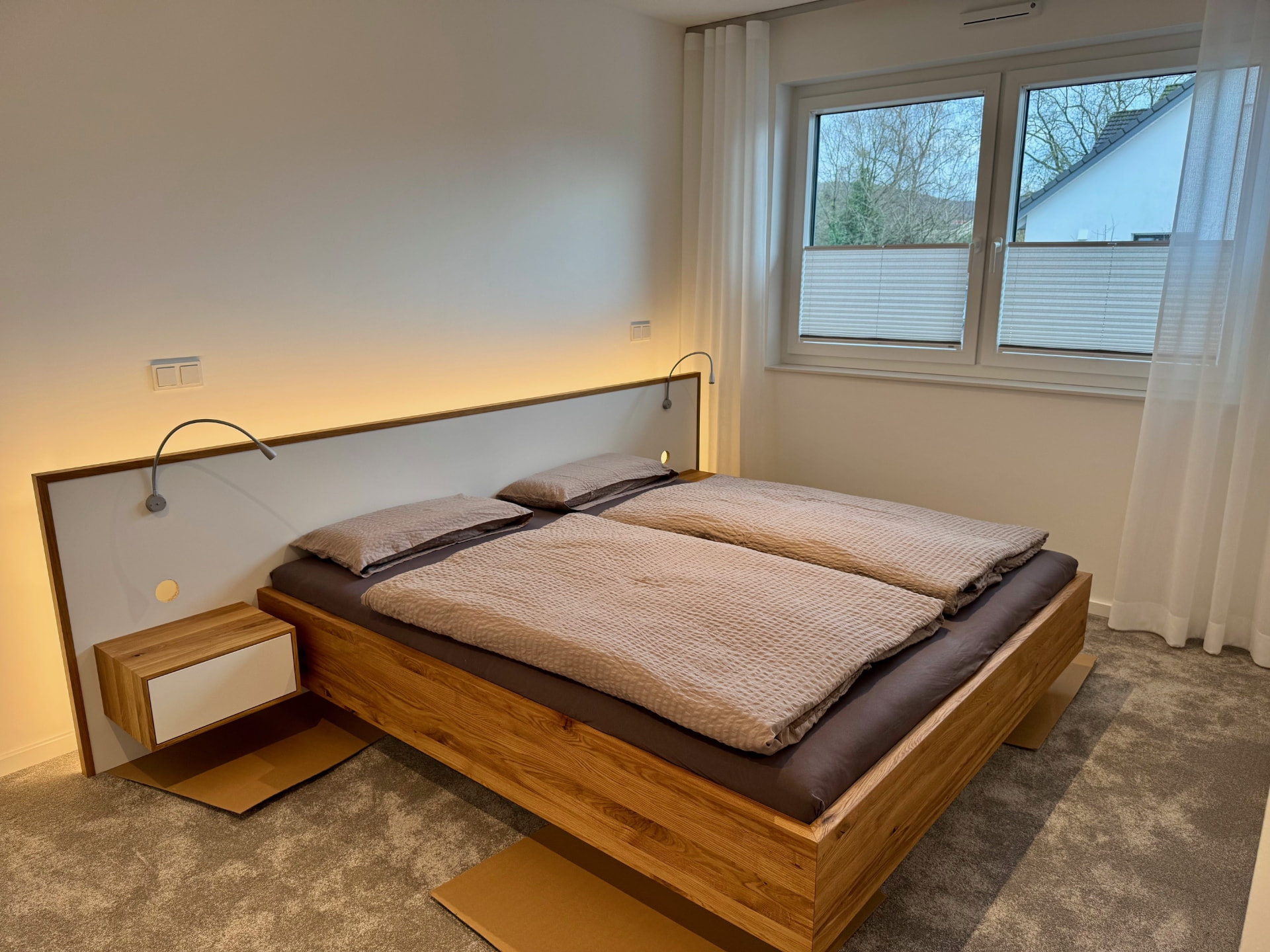 Schlafzimmer mit Eichen-Doppelbett, beleuchtetem Kopfteil und Nachtkonsole.